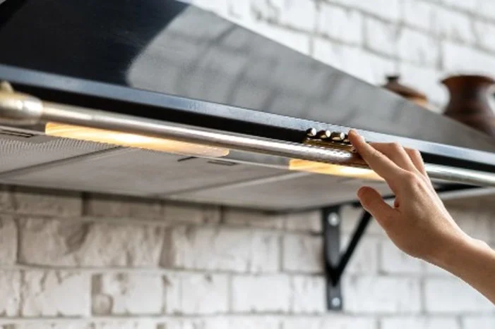 Hand schaltet Dunstabzugshaube ein